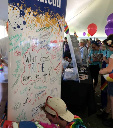 Attendee of the Portsmouth Pride event in New Hampshire  writing an SNHU banner​