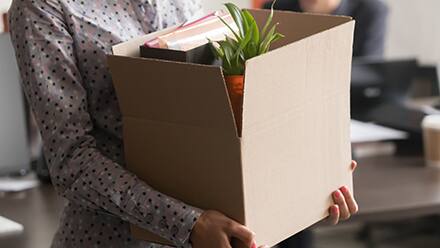 A person carrying a box as they leave their job