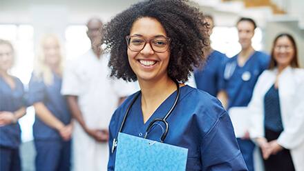A nurse with a stethoscope and clipboard surrounded by six other healthcare professionals.