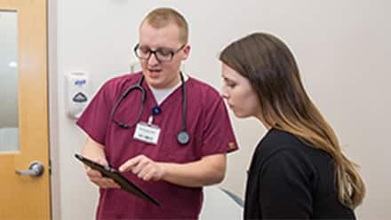 A male nurse showing charts to a female patient discussing the types of nursing jobs