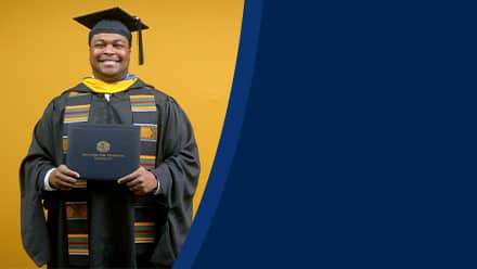 Aaron Davenport, a 2025 master's in finance graduate from SNHU, wearing a cap and gown and holding his diploma.