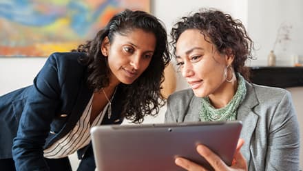 Two business professionals looking at a laptop and considering the best reasons for getting an MBA Degree.