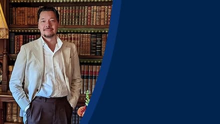 Dr. Christopher Lee, an associate dean of English programs at SNHU, standing in front of a bookcase. 