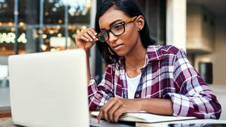 A person sitting by a window, researching certificate  programs on a laptop