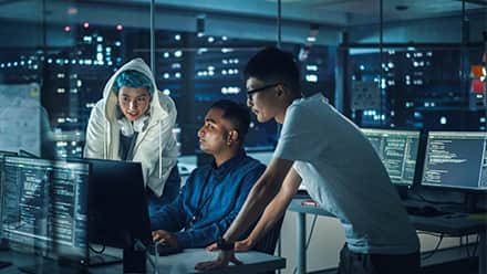 Three people in a computer lab working on a cybersecurity project.
