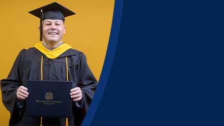 David Wallace, a 2025 SNHU graduate who earned his bachelors in business administration wearing his cap and gown in front of a yellow background.