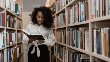 A woman with an English literature degree reading a book in a library