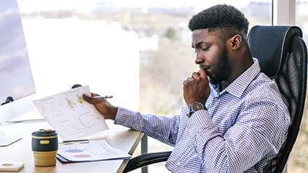 A man contemplates the difference between finance vs accounting, looking at a series of charts at his desk.