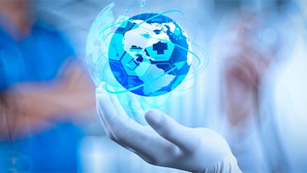 A gloved hand holding a glowing globe with medical icons and network lines, against a blue clinical background.