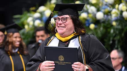 An SNHU graduate at Commencement earning their degree.