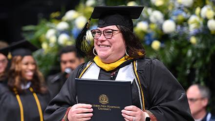 An SNHU graduate at Commencement earning their degree.