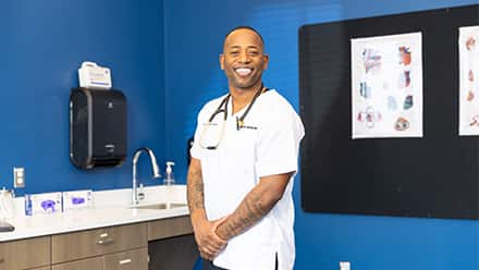 Anthony Gray, an SNHU graduate with a Master of Science in Nursing, dressed in white scrubs with a stethoscope around his neck.