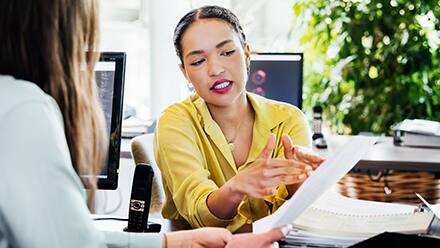 An employee holding her resume and listening to her mentor tell her how to become a manager