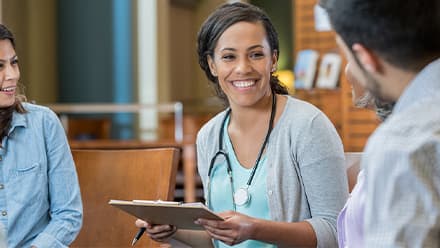 A certified health education specialist holding a clipboard and speaking with a community member.