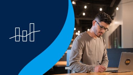 Naeem Jaraysi, who earned his master's degree in marketing at SNHU, taking notes from his laptop to the left of an icon showing data