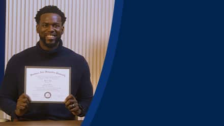 Kitrick Bell, a 2025 SNHU graduate who earned his master's in information technology with a concentration in software application development, smiling and holding his diploma.
