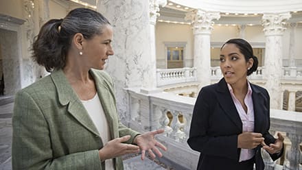 Two criminal justice professionals in conversation as they walk around courthouse hallways.