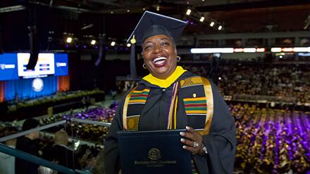 SNHU business administration graduate Robyn Roberts in her cap and gown and holding her diploma at the SNHU commencement ceremony.