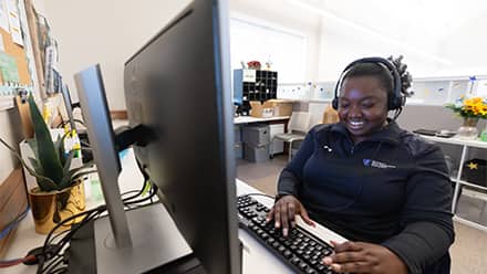 A student support staff member at Southern New Hampshire University (SNHU) smiling while on a call with a student.