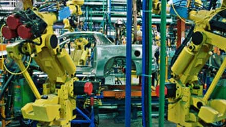 Large yellow robotics on an automobile assembly line where a manager with a technical degree might work