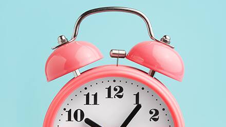 The top half of a pink analog clock used for time management, set against a blue background