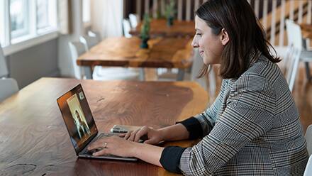 A healthcare student sitting at a table, participating in a webinar on her laptop.