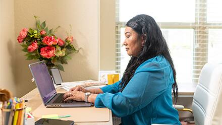 An adult college student researching at her laptop, to represent finding a transfer-friendly college.