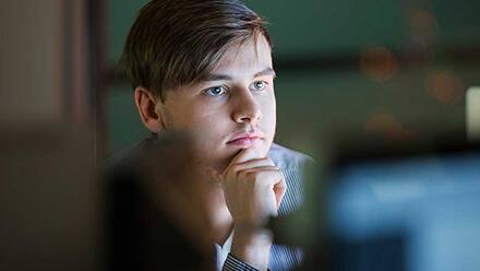 Programmer​ sitting at a desk looking at a computer screen.