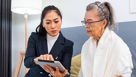 A woman sitting with a caseworker looking at an iPad.