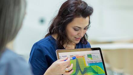 A professional with an MPH degree walking three cross-departmental teammates through a graph on her laptop.