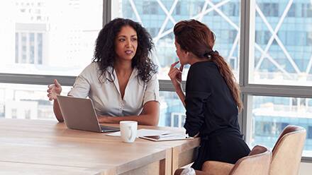 Two HR professional's in discussion at a meeting