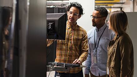Three IT professionals working at a computer terminal