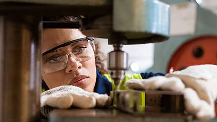 A mechanical engineer wearing protective equipment while working with machinery.
