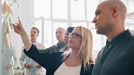 Business professionals in a meeting looking at a whiteboard.