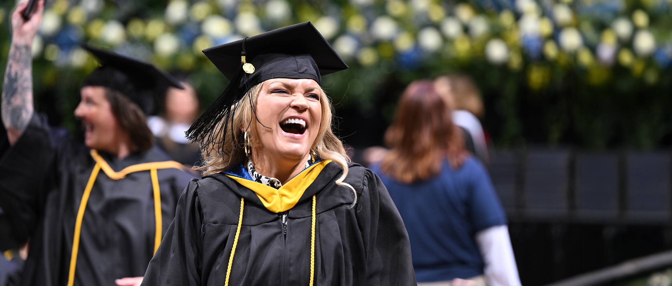 SNHU graduate at commencement, smiling while walking to get her diploma.