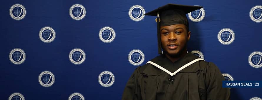 Online Associate Degree graduate Hassan Seales in cap and gown following his 2023 graduation ceremony from Southern New Hampshire University.