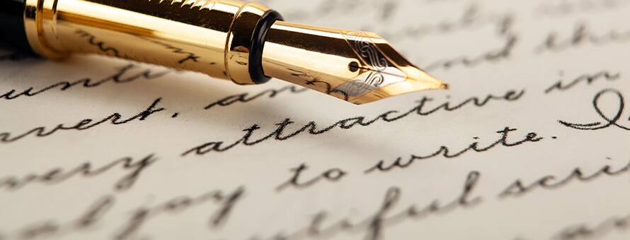 A gold pen resting on a sheet of paper with personal growth quotes written in cursive.