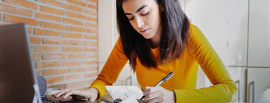 A woman in a yellow shirt working on her college capstone project