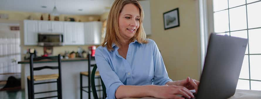 A woman sitting at a table going through a career assessment on a laptop