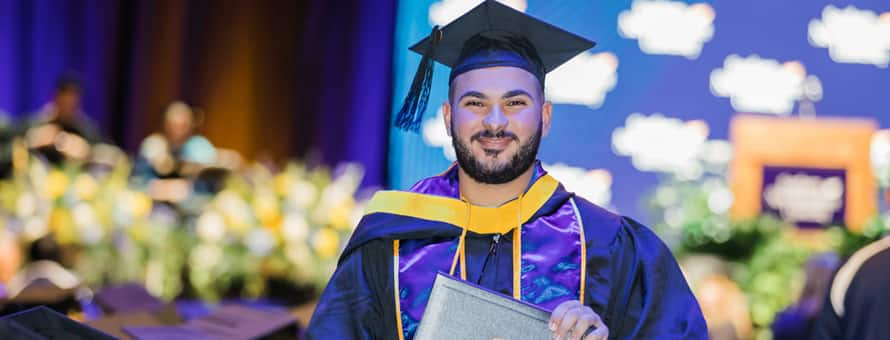 A graduate in cap and gown after crossing the SNHU Arena stage at Commencement.