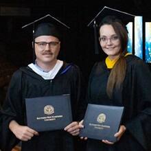 Parker and Jessica Bryant in their cap and gown and holding SNHU degrees.