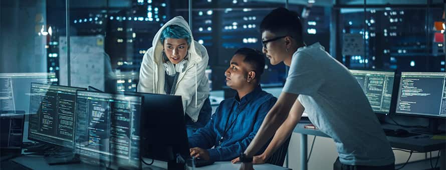 Three people in a computer lab working on a cybersecurity project.