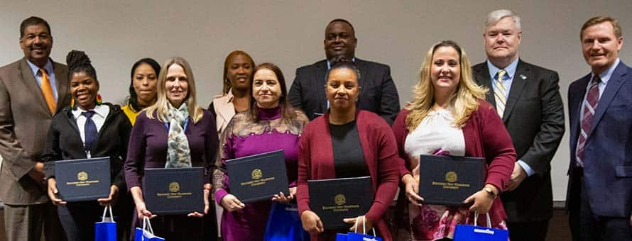 The 7 MassDOT and MBTA employees who graduated from College for America with their supporters.