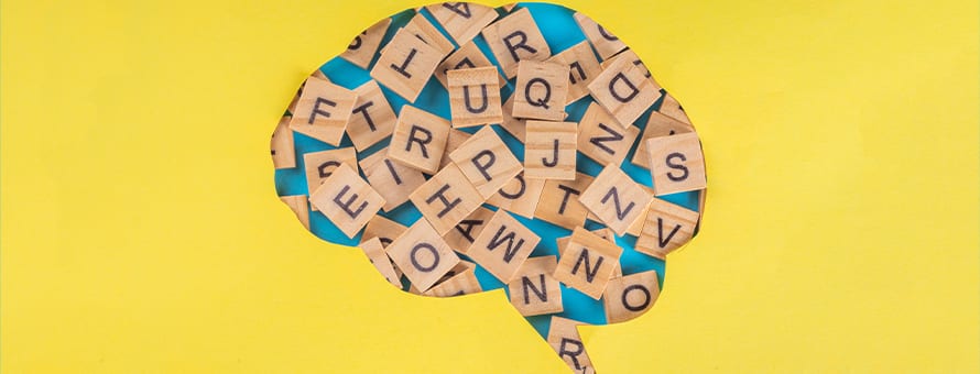 A speech bubble cut from a yellow background and filled with wooden blocks with letters on them.