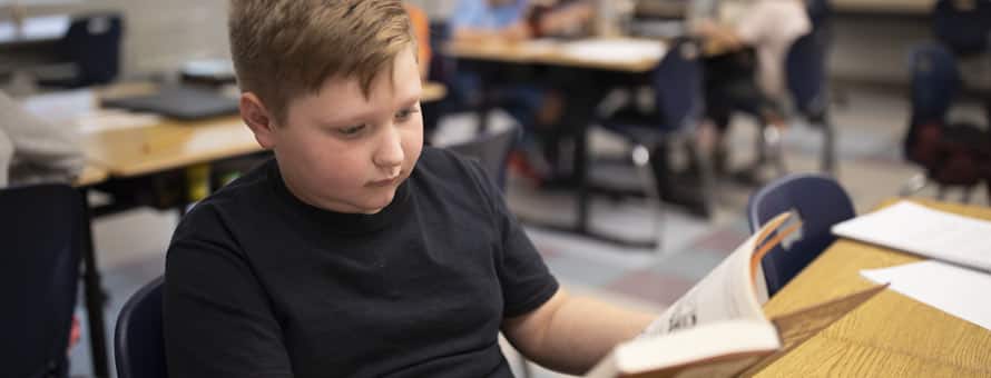 Photo of a boy with dyslexia reading a book.