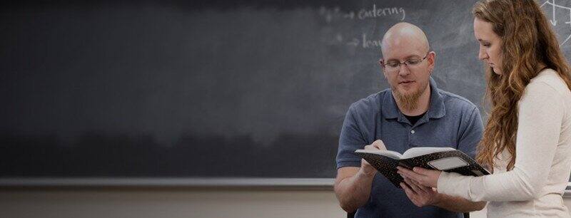 Teacher viewing the work of  a student in a notebook