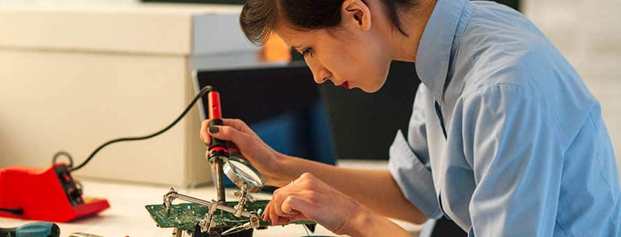 A female electrical engineer using a soldering tool to build an electronic component.