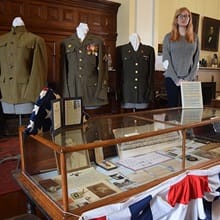 Elizabeth Gitschier standing with a Civil War display she created including replica uniforms, and other displays.