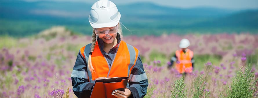 Environmental scientists in a field wearing protective equipment and taking notes.