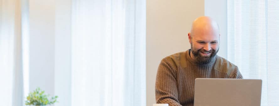 SNHU student wearing a brown sweater while working on his laptop.